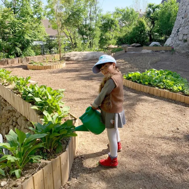 A young girl watering plants at a Family Friends event, promoting environmental awareness and community involvement