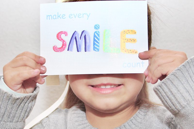 Child holding a sign that says 'Smile', spreading positivity and joy